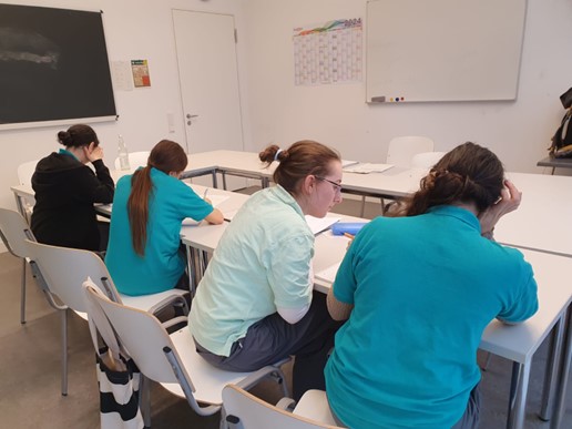 Vier Schülerinnen sitzen im Klassenraum und bearbeiten gemeinsam Aufgaben